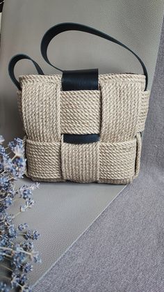 a white purse sitting on top of a couch next to a vase filled with flowers