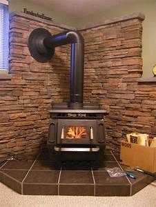 a room with a stone wall and a wood burning stove