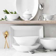 white dishes and utensils are arranged on a shelf