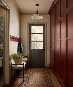 a hallway with wooden cabinets and a bench in front of the door that leads to another room