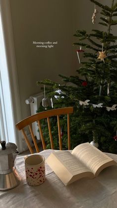 an open book sitting on top of a table next to a coffee pot and cup