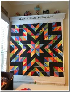 a colorful quilt hanging on the wall next to a window