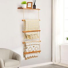 a wall hanging shelf with three different pieces of fabric on it and a chair in the background