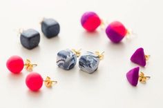 four pairs of earrings with different colors and shapes on white surface next to each other