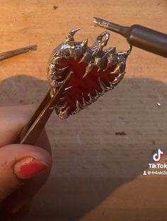 a close up of a person's hand holding a metal object with red flowers on it