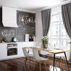 a kitchen with white cabinets and chalkboard walls in the back wall, along with wooden flooring