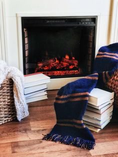 a pile of books sitting on top of a wooden floor next to a fire place