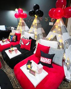 a living room filled with red couches covered in black and white pillows next to balloons