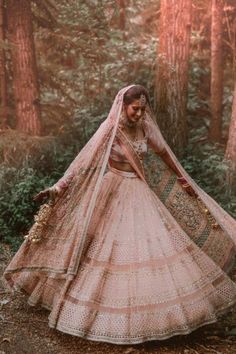 a woman in a wedding dress is standing in the woods with her veil pulled back