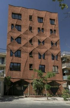 the building is made out of bricks and has many windows on each side with triangular shapes