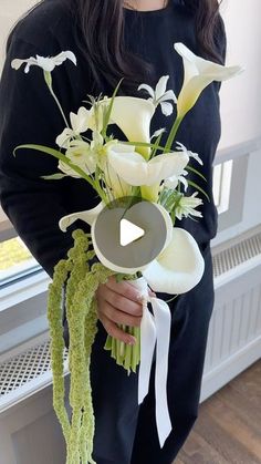 a woman holding a bouquet of white flowers