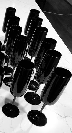 a bunch of wine glasses sitting on top of a table next to each other in black and white