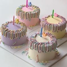 three birthday cakes with candles and icing on top of each cake, sitting on a white tray