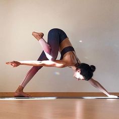 a woman is doing yoga on the floor with her legs spread out and one leg bent up