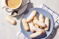 powdered sugar cookies on a blue plate next to a cup of coffee and spoon