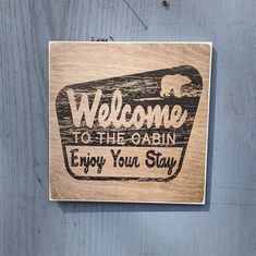 a wooden sign that says welcome to the cabin enjoy your stay