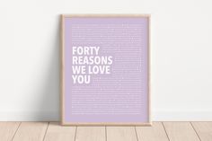 a framed poster with the words forty reasons we love you in white on a light purple background