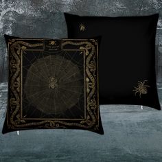 two black and gold pillows with spider web on them, one in front of the other