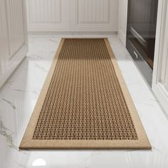 a kitchen with white cabinets and an area rug on the floor in front of it