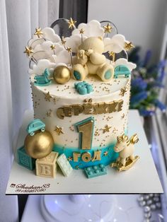 a birthday cake decorated with teddy bears and gold stars on the top, sitting on a table in front of a window