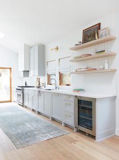 a kitchen with an oven, sink and shelves on the wall next to a door