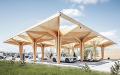 a white car is parked in front of a covered gas station with grass and trees