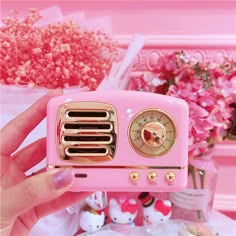 a pink radio sitting on top of a table with hello kitty figurines next to it