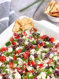 a white platter filled with olives, feta cheese and pita chips