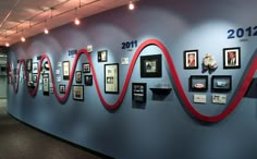 a wall with many pictures on it and red ribbon hanging from the side, along with framed photographs