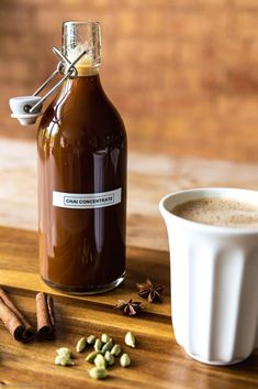 a cup of coffee sitting next to a bottle of cinnamon spice and some spices on a wooden table