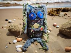 a crocheted stuffed animal sitting on top of a sandy beach