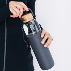 a woman is holding a water bottle in one hand and a wooden lid on the other