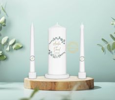 two white candles sitting on top of a wooden stand