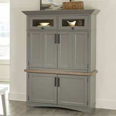 a grey cabinet with two doors and shelves on the top, next to a white table