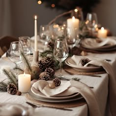 the table is set with pine cones, candles and napkins for christmas dinner guests to enjoy