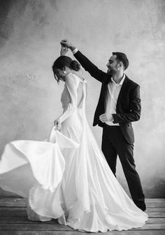 a bride and groom dancing together in black and white