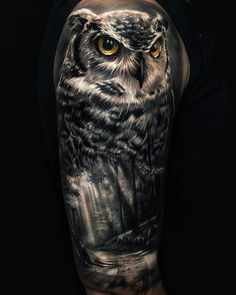 an owl with yellow eyes is shown on this man's arm and shoulder tattoo