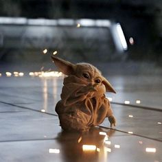 a baby yoda doll sitting on the floor in front of some lit up candles