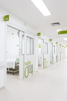 an empty hospital hallway with white walls and green signs on the doors that read suite c