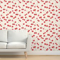 a white couch sitting in front of a wall with red flowers on it's side