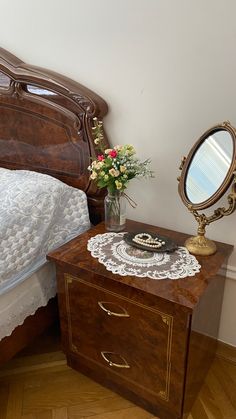 a bedroom with a bed, nightstand and mirror on it's side table in front of the bed