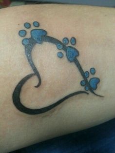 a tattoo on the arm of a woman with blue paw prints and a letter j