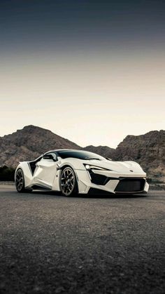 a white sports car parked on the side of a road in front of some mountains