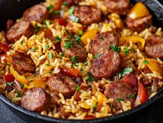 a skillet filled with rice, sausage and peppers