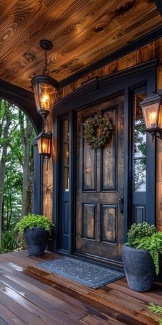 a wooden porch with potted plants and two lights on the front door, along with a wood floor