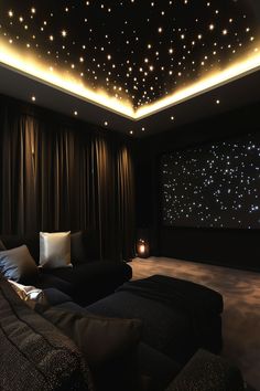 a living room with stars on the ceiling and black couches in front of a projector screen