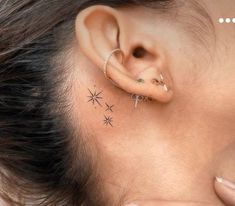 a woman's ear with three small stars on it