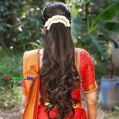 a woman with long hair wearing a red and orange sari