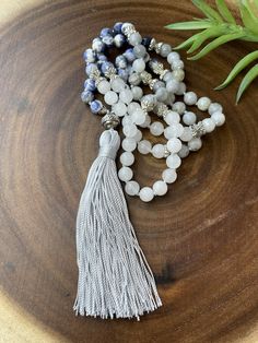 This neutral tone necklace is hand knotted with sodalite, gray labradorite, and white jade. There are silver plated antique style spacers in between the beads. The gray tassel with a nepal style bead measures 4.5 inches long. The necklace measures 33 inches long without tassel. It's definitely a stunning necklace! Beaded Tassel Necklace, Enamel Necklaces, White Jade, Lava Bead, Beaded Tassels, Stunning Necklace, The Gray, Neutral Tones, Antique Style