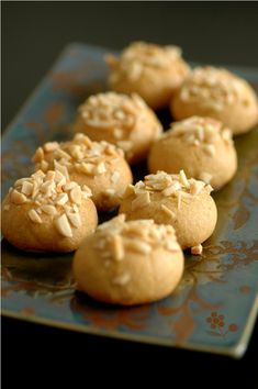 some cookies are sitting on a blue and orange plate with almond toppings in the middle